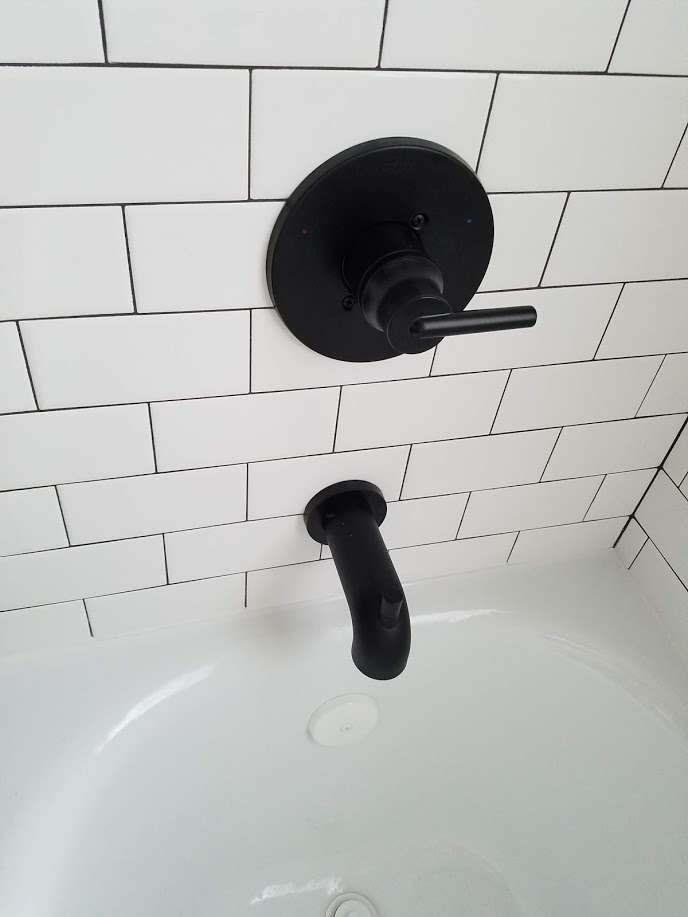 subway tile shower with black faucet
